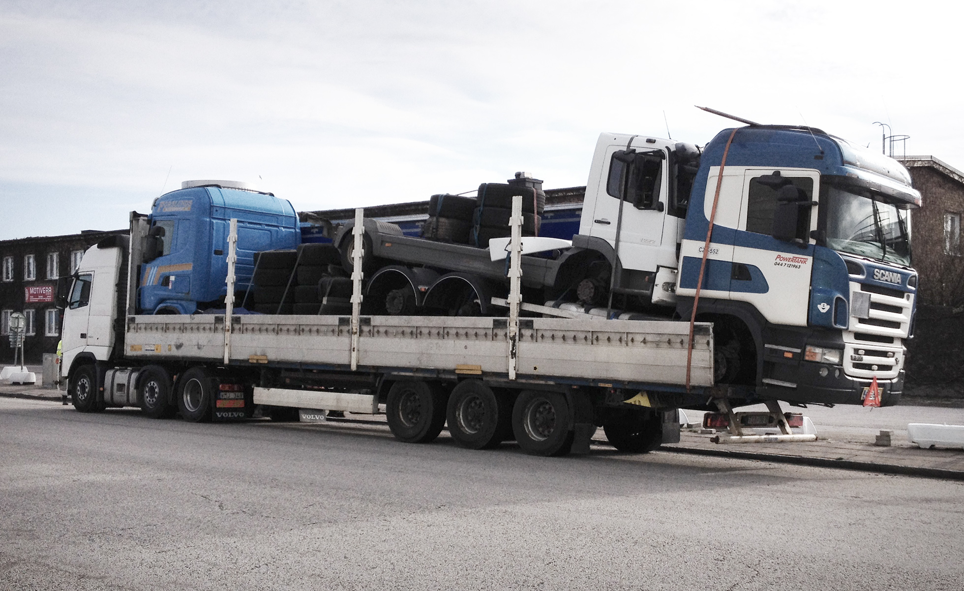 Tre lastbilar med körförbud som är lastade på en lastbil, fästa med enbart spännband. Även lastbilen som de andra fordonen står på har körförbud. Sannolikt ska de transporteras otillåtet utomlands. Foto: Miljöförvaltningen Malmö